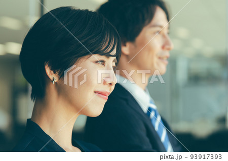 窓際に立つ男女のビジネスマン 93917393