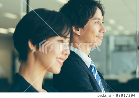 窓際に立つ男女のビジネスマン 窓際に立つ男女のビジネスマン 93917394