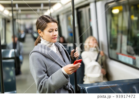 Young woman with phone in public transport Young woman with phone in public transport 93917472