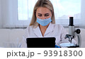 female research chemist scientist in a protective mask and gloves, dressed in a medical suit, with a 93918300