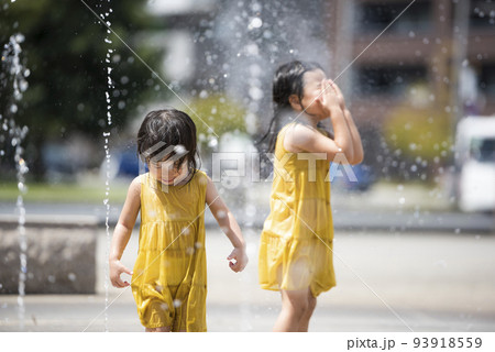 駅前広場の噴水で水浴びして遊んでいる女の子 93918559