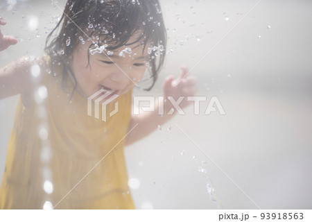 駅前広場の噴水で水浴びして遊んでいる女の子 93918563