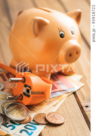 Electric plug, euro money and piggy bank on the wooden table. Concept of increasing electric prices. 93918722