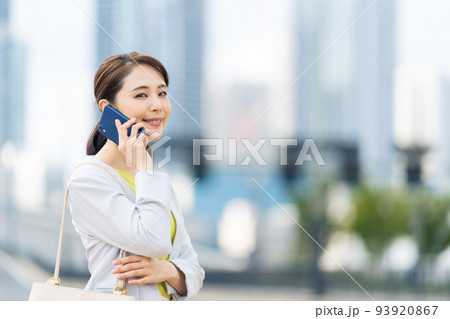 都市をバックにスマホで通話する女性 都市をバックにスマホで通話する女性 93920867