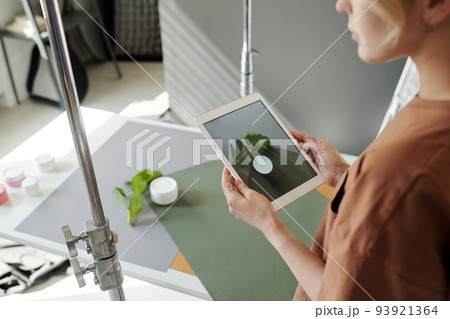 Hands of young assistant of photographer holding tablet over composition 93921364