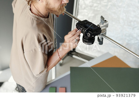 Above view of bearded man in t-shirt adjusting settings of camera on slider Above view of bearded man in t-shirt adjusting settings of camera on slider 93921379