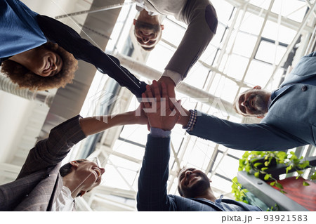 Happy group of multi ethnic coworkers stacked hands together as concept of corporate unity Happy group of multi ethnic coworkers stacked hands together as concept of corporate unity 93921583