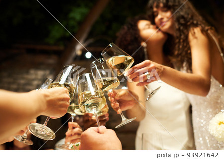 Group of flutes with champagne held by company of friends and brides Group of flutes with champagne held by company of friends and brides 93921642