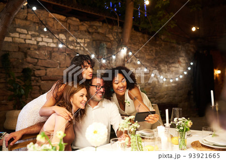 Young African American bride holding smartphone in front of wedding guests 93921665