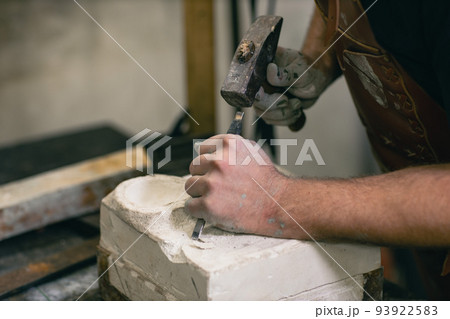 Man sculptor creates sculpt bust gypsum human woman sculpture with hammer. Statue craft creation workshop. 93922583