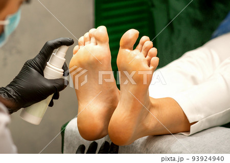 A woman getting a pedicure and pedicurist moisturizing female feet with lotion spraying in a beauty salon A woman getting a pedicure and pedicurist moisturizing female feet with lotion spraying in a beauty salon 93924940