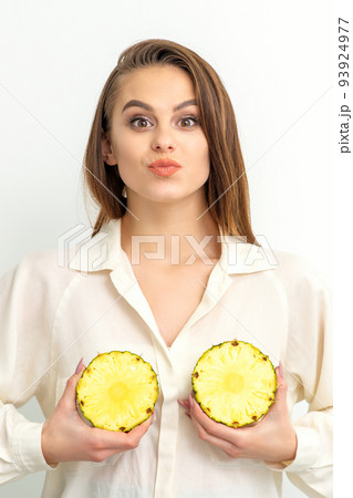 Young Caucasian smiling woman holding slices pineapple over white background, breast health concept 93924977