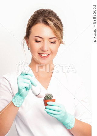 A smiling female beautician holds little green cactus with the razor in her hands. Hair removal concept A smiling female beautician holds little green cactus with the razor in her hands. Hair removal concept 93925053