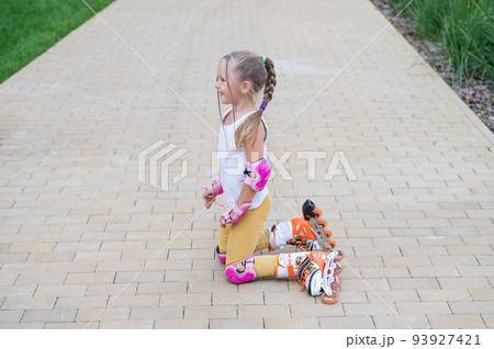 Little girl learns to roller skate and falls. Little girl learns to roller skate and falls. 93927421