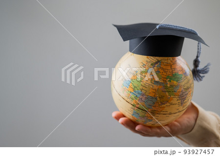 Woman holding a globe wearing a graduation cap.  93927457
