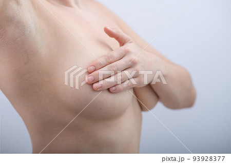 Caucasian woman self checks for breast cancer on white background.  93928377