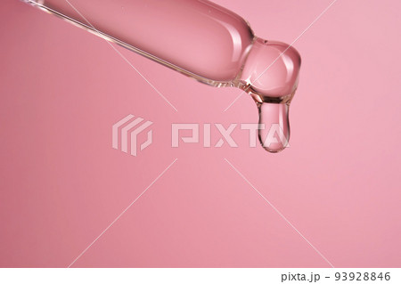 Dropper with serum or cosmetic oil on a pink background. 93928846