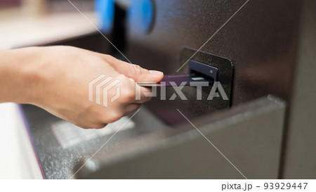 Faceless woman inserts bank card at ATM.  93929447