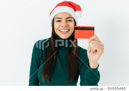 Portrait of cheerful young woman wearing santa hat 93930460