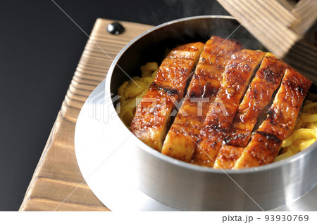 鰻の蒲焼きが入っている熱々の釜飯を黒背景で撮影 93930769