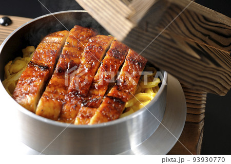 鰻の蒲焼きが入っている熱々の釜飯を黒背景で撮影 93930770