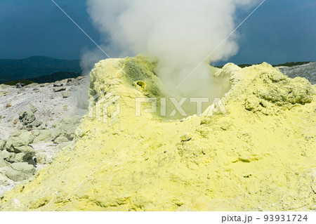 cone of sulfur deposits around a fumarole in a solfataric field illuminated by the sun against a stormy landscape in the distance cone of sulfur deposits around a fumarole in a solfataric field illuminated by the sun against a stormy landscape in the distance 93931724