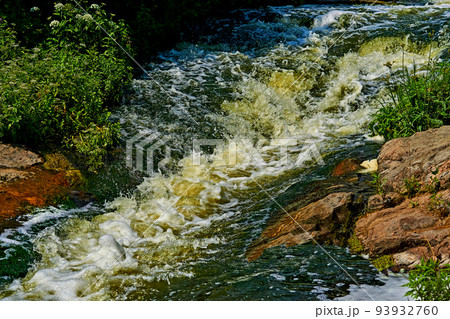 Stormy fast foaming stream of a strong mountain river on a warm day Stormy fast foaming stream of a strong mountain river on a warm day 93932760