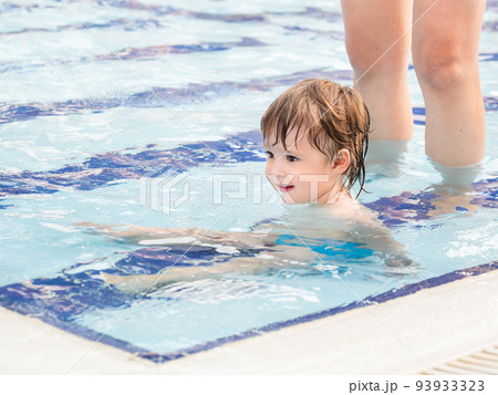 Toddler floats in paddling pool. Teaching children to swim from early childhood. Sport, active lifestyle and physical development. Toddler floats in paddling pool. Teaching children to swim from early childhood. Sport, active lifestyle and physical development. 93933323