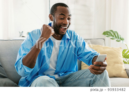 Great news. Overjoyed black man holding smartphone and celebrating success, looking at cellphone and raising fist 93933482