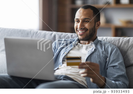 Online Shopping. Cheerful Handsome Black Man Using Laptop And Credit Card Online Shopping. Cheerful Handsome Black Man Using Laptop And Credit Card 93933493