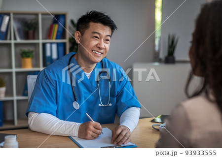 Cheerful friendly mature korean man doctor consulting young african american lady patient in clinic 93933555