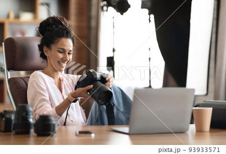 Beautiful creative woman photographer working, using laptop and camera 93933571