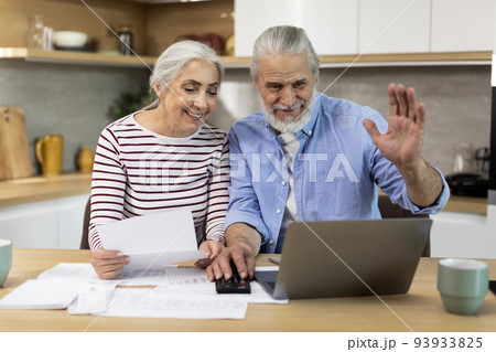 Senior Spouses Making Video Call With Accountant While using Laptop In Kitchen 93933825