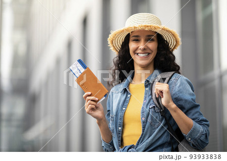 Closeup of cheerful pretty woman holding passport and tickets 93933838