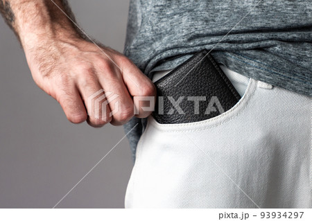 The concept of saving money. The man puts the wallet in the front pocket of the white jeans. Close up The concept of saving money. The man puts the wallet in the front pocket of the white jeans. Close up 93934297