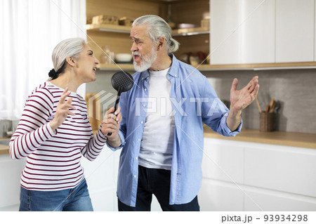 Positive Senior Couple Having Fun In Kitchen Interior, Singing And Dancing 93934298