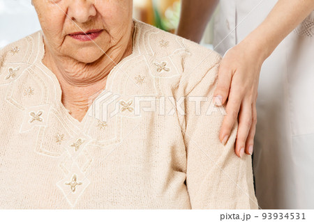 Nurse put her hand on the shoulder of a senior woman. Close-up. The concept of nursing home 93934531