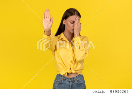 Female Gesturing Stop Covering Face With Hand Protesting, Yellow Background 93936262