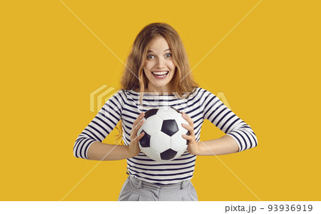 Young woman holding football and looking at camera with funny, excited face expression Young woman holding football and looking at camera with funny, excited face expression 93936919