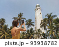 Woman Traveler in Front of Famous Landmark of Sri Lanka with smartphone, Dondra Lighthouse 93938782