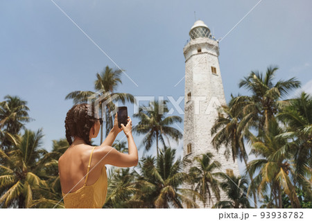 Woman Traveler in Front of Famous Landmark of Sri Lanka with smartphone, Dondra Lighthouse 93938782