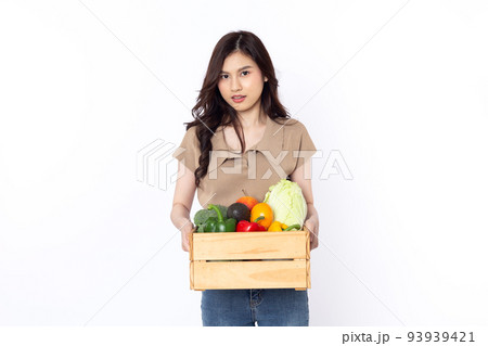 Cheerful smiling Asian woman holding a wooden box of vegetables after shopping isolated on a white background Cheerful smiling Asian woman holding a wooden box of vegetables after shopping isolated on a white background 93939421