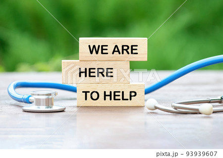 WE ARE HERE TO HELP text on wooden blocks on a green background WE ARE HERE TO HELP text on wooden blocks on a green background 93939607