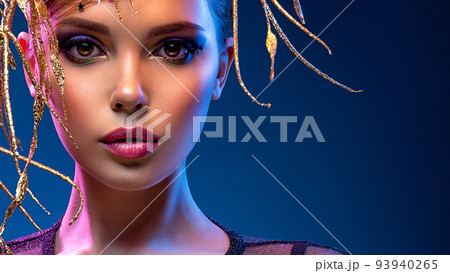 Stylish fashion model with a golden decoration around her face. Beauty style. Art portrait of a beautiful woman with bright makeup. Closeup model face with vivid eye make-up. 93940265