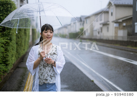 雨の中を傘をさして歩く女性 雨の中を傘をさして歩く女性 93940380