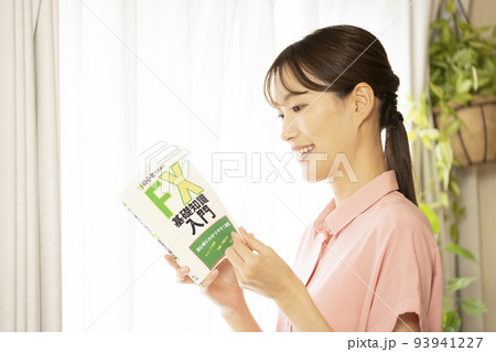 窓際で笑顔でFXの本を持つ女性 93941227