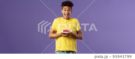 Happy birthday to me. Portrait of upbeat, excited hispanic man with dreads celebrating b-day, holding plate cake with lit candle, smiling amused, making wish, purple background 93943799