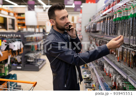 a customer in a tool store chooses a drill for metal talking on the phone 93945551