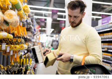 a customer holds a bubble level in his hands in a store of building materials and finishing fixtures a customer holds a bubble level in his hands in a store of building materials and finishing fixtures 93947061