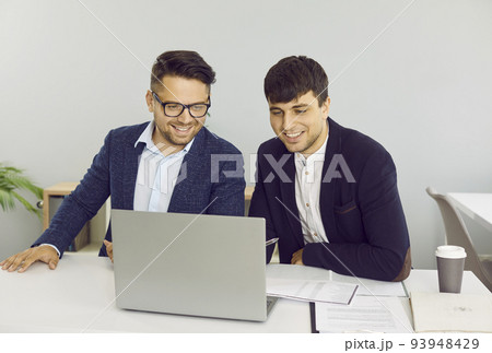 Two friendly male colleagues are working together in office on joint startup project. 93948429